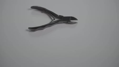 Hand Moves Shiny Nail Clippers on White Surface