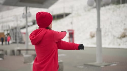 Back View of Woman Stretching Arms Outdoors in Winter