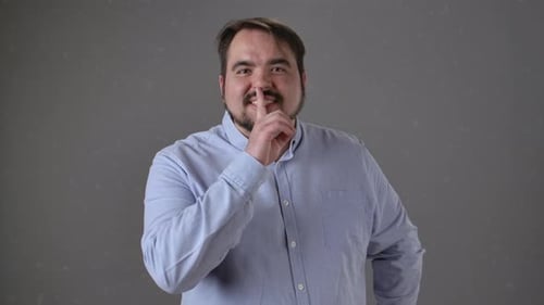 Person in Blue Shirt Making Silence Gesture with Index Finger