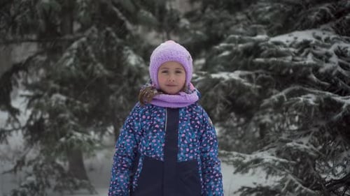 Girl Stands in Falling Snow in Snowy Forest