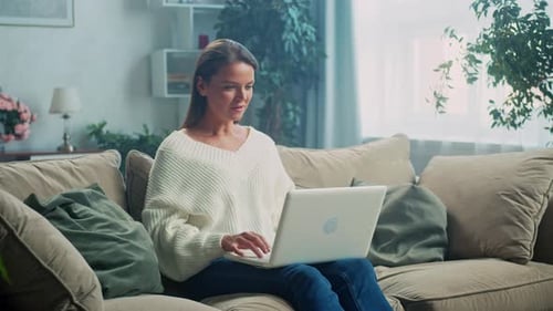 Woman Working on Laptop on Couch at Home