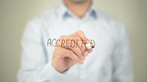 Man Writes Accredited on Transparent Surface