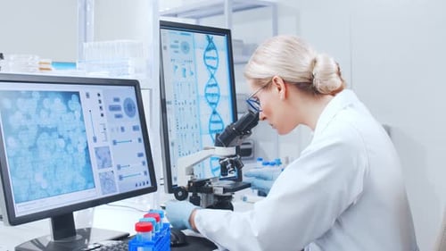 Focused Scientist Analyzing Samples Under Microscope in Lab