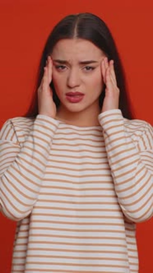 Young Woman Suffering Headache Touching Temples in Studio