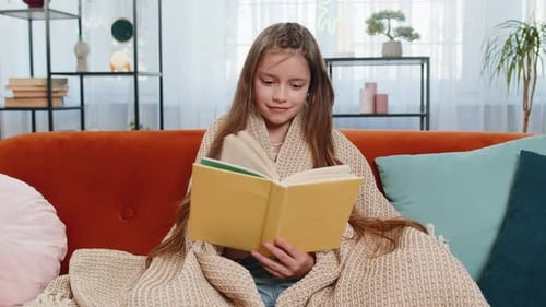 Child Wrapped in Blanket Relaxing Reading Book Turning Pages Smiling Enjoying Literature Education