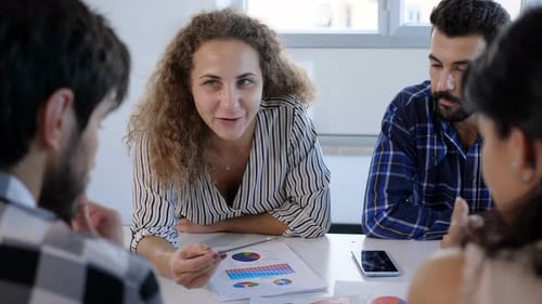 Team Discussing Data at Table in Bright Office