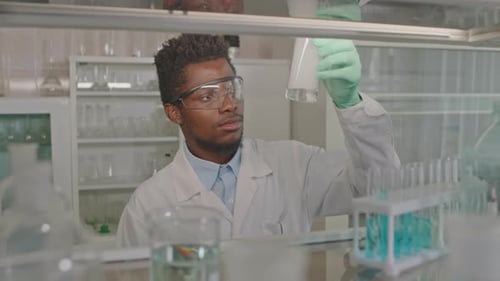 Young Adult Scientist Examining Beaker in Laboratory
