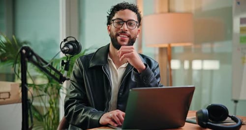 Happy, laptop and face of man with mic in studio for podcast, broadcast and interview for talk show