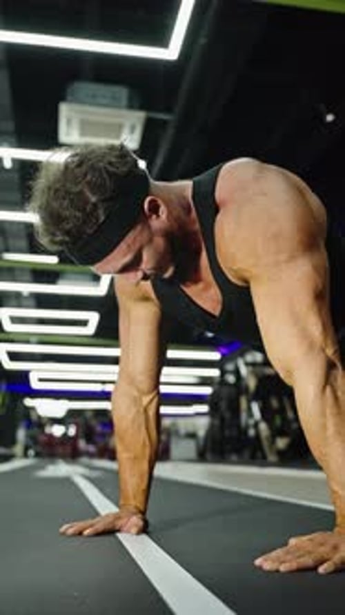 Focused Athlete Performing Intense Pushup Exercise on Indoor Gym Track Showcasing Muscular Upper