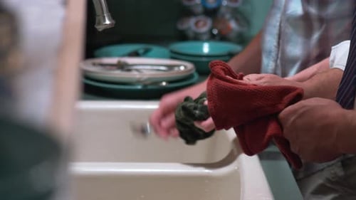 Adults Washing Dishes by Hand at the Sink