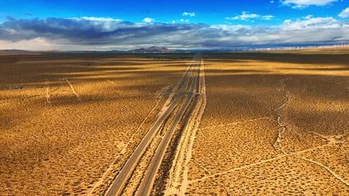 View of a desert in California covered with little bushes. Highway lies along the landscape.