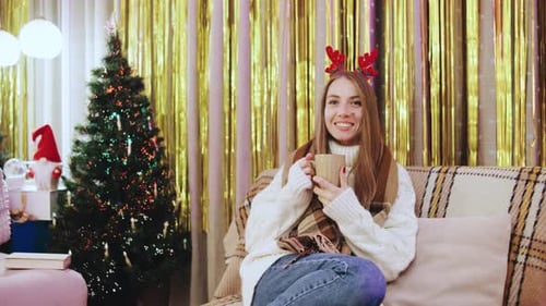 Woman Smiling With Mug on Couch During Christmas