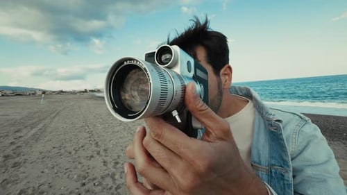 Man Filming with Vintage Camera on Beach