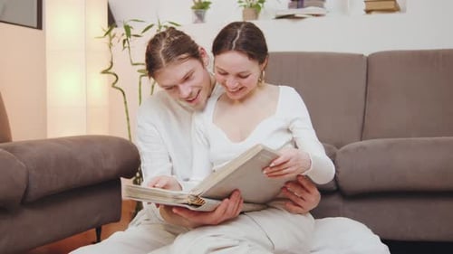 Happy Couple Laughing, Looking at Photo Album at Home