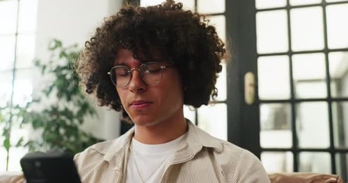 Man Using Smartphone While Relaxing on Sofa Indoors