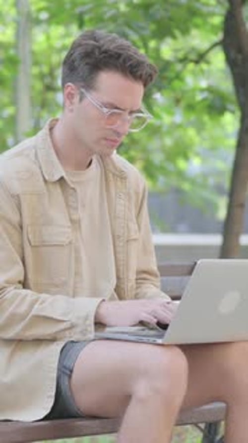 Young Man Works on Laptop in Outdoor Park