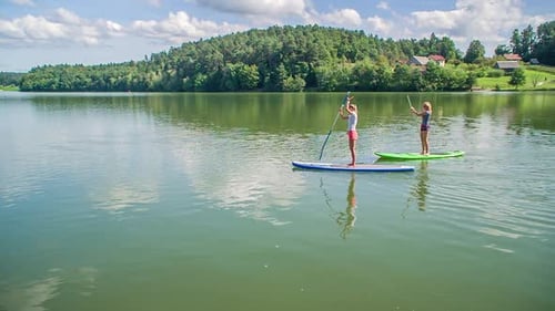Two young women on paddleboards in Slovenia, on a bright afternoon