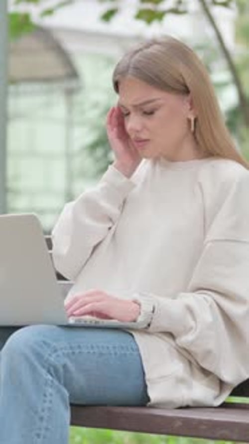 Woman Suffering Headache While Working on Laptop Outdoors