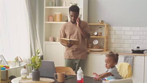 Man on Phone with Child in Kitchen