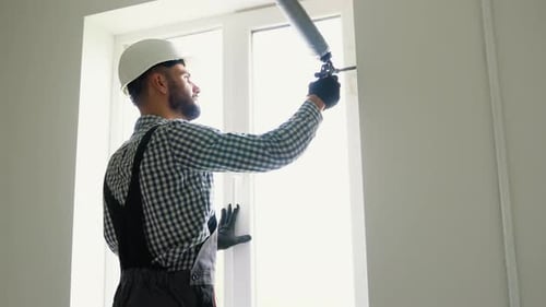 Worker is Applying Polyurethane Foam to Fill Gap Between Sash and Window Frame