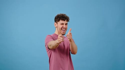 Playful Man Makes Finger Guns on Blue Background