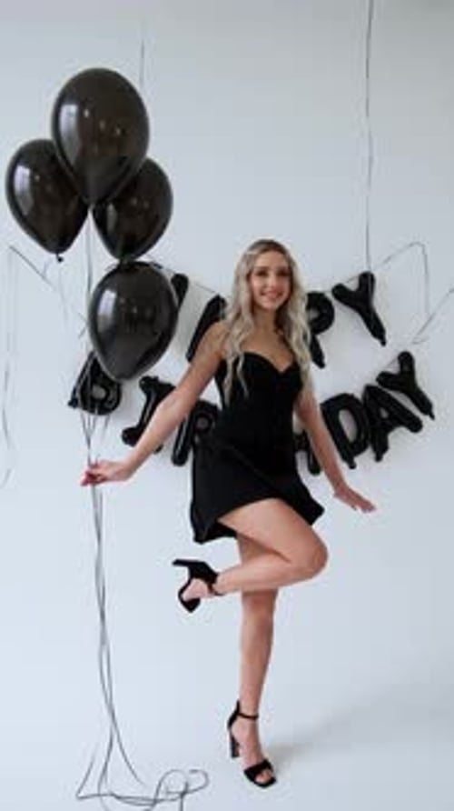 Blonde Woman Celebrating Birthday with Black Balloons
