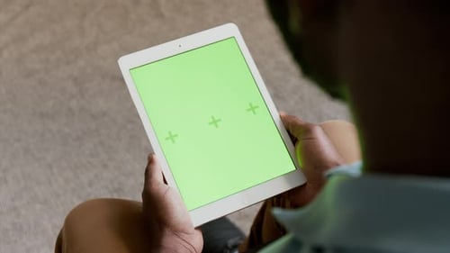 Unbekannter schwarzer Mann schaut auf Tablet mit grünem Bildschirm