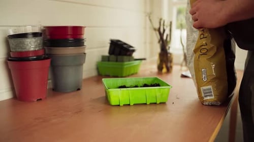 Man Putting Garden Soil On Plastic Pot. - close up shot
