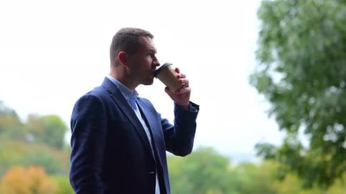 Portrait of One Successful Male Professional Standing Outdoors in Nature Drinking Coffee From Paper