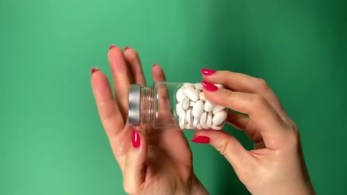 Hands Holding Bottle with White Pills