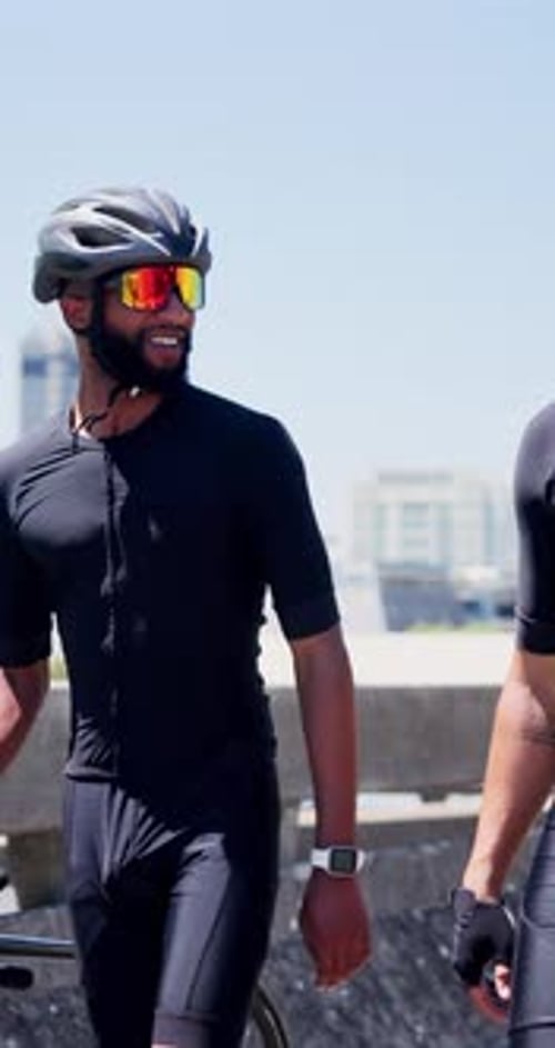 Friends, bicycle and talk in city with fitness, smile and conversation with break on urban bridge