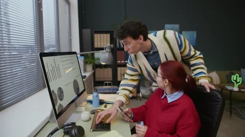 Male Colleague Providing Help to Female Manager Working on Office Computer
