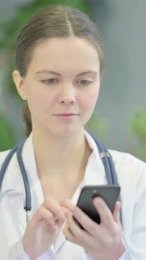 Doctor in Lab Coat Using a Mobile Phone