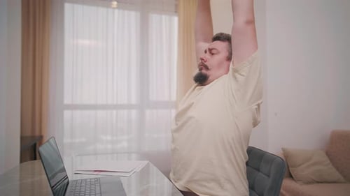 Middle aged man stretching at desk during home office break