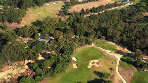 Aerial View of Golf Course Surrounded By Lush Greenery on Sunny Day