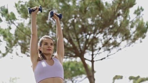 Woman Working Out With Dumbbells in a Park