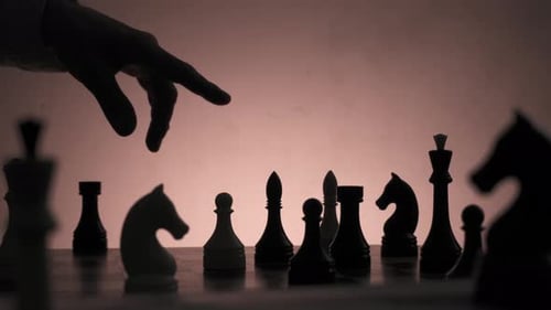 Em uma sala mal iluminada, um pensamento humano e uma mão movendo peças no tabuleiro de xadrez