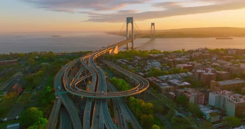Multiple roads leading to a beautiful long bridge. Amazing Whitestone bridge across the river at sun