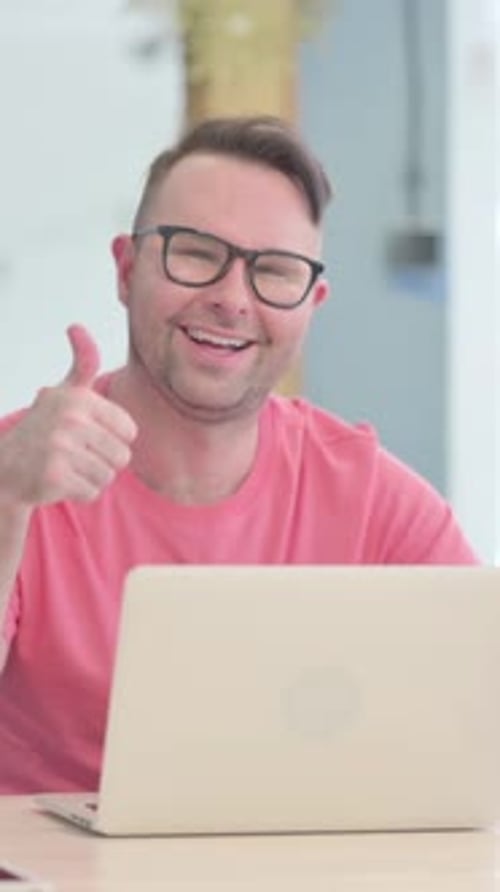 Man in Glasses Working on Laptop Gives Thumbs Up
