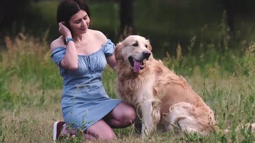Woman Cuddles with Golden Retriever in Sunny Field