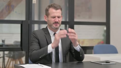 Businessman having Migraine sitting in Office