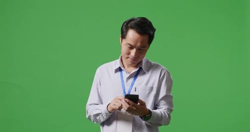 An Asian Business Man Using Mobile Phone On Green Screen Background In The Studio