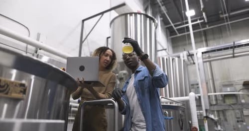 Brewers with Laptop Inspecting Beer Below Fermenting Tanks 10 Seconds or Greater