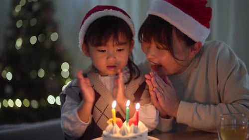 Woman and Child Blow Out Birthday Candles at Christmas