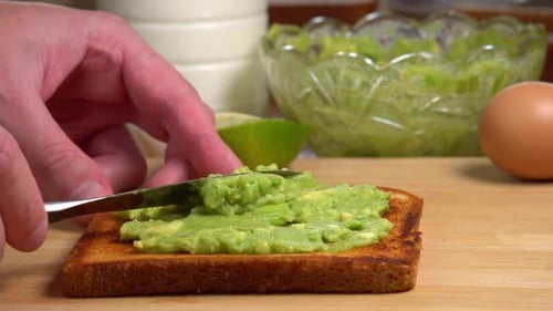 Spreading Mashed Avocado on Toast for Breakfast