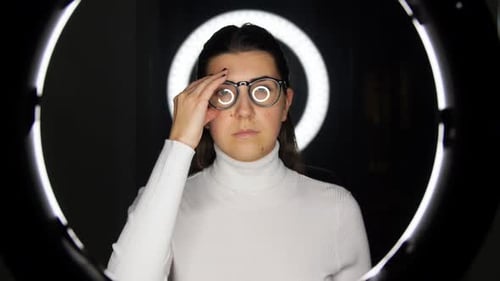 Woman Puts on Glasses in front of Ring Light