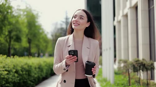 Female Typing Message on Smartphone While Taking Walk and Having Cup of Coffee