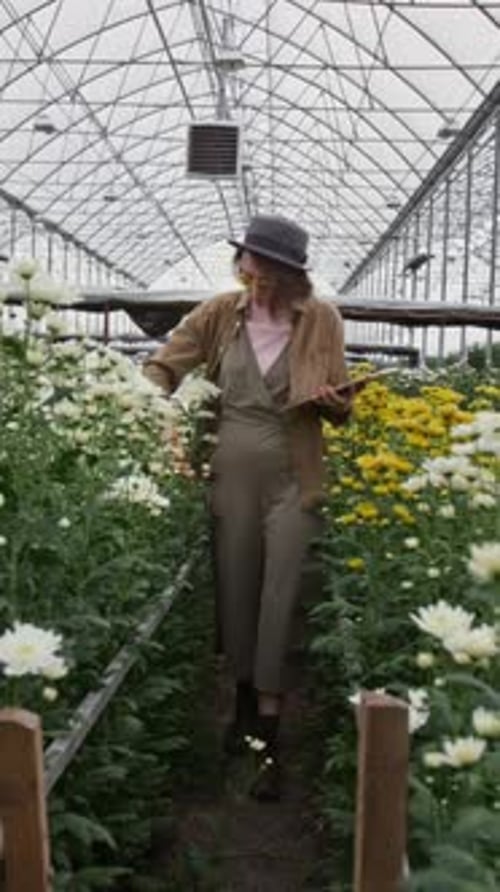 Stylish Young Adult Among Flowers in Greenhouse