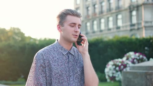 Young Caucasian Man Walking in City and Talking on Smartphone Joyful Caucasian Male Use Smartphone