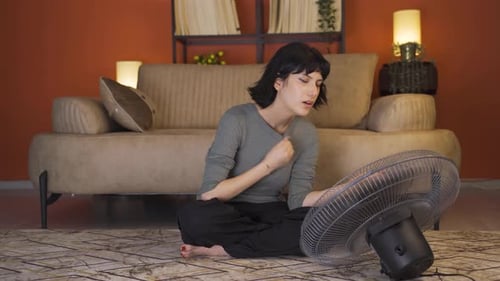 Woman Cooling Down with Fan Indoors